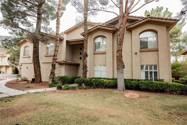 mediterranean / spanish-style house with stucco siding, a front lawn, and a tiled roof