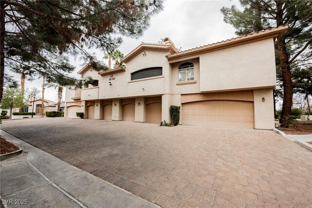 mediterranean / spanish house with stucco siding, decorative driveway, and an attached garage