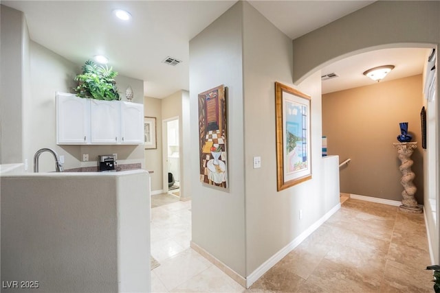 interior space featuring a sink, visible vents, arched walkways, and baseboards