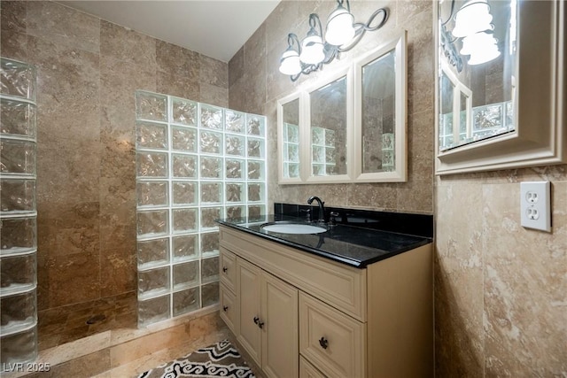 full bath featuring a walk in shower, tile walls, and vanity