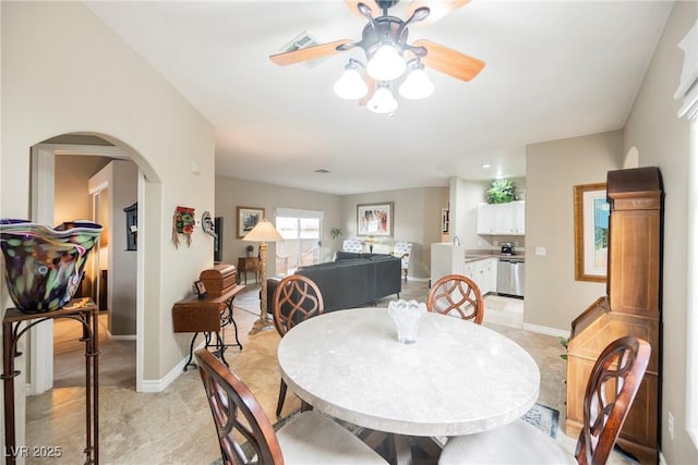 dining area featuring arched walkways, visible vents, a ceiling fan, and baseboards