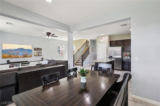 dining room featuring a ceiling fan, visible vents, baseboards, and stairs