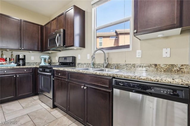 kitchen featuring light stone counters, light tile patterned floors, stainless steel appliances, a sink, and dark brown cabinets