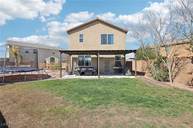 rear view of house featuring a trampoline, a yard, stucco siding, a patio area, and a fenced backyard