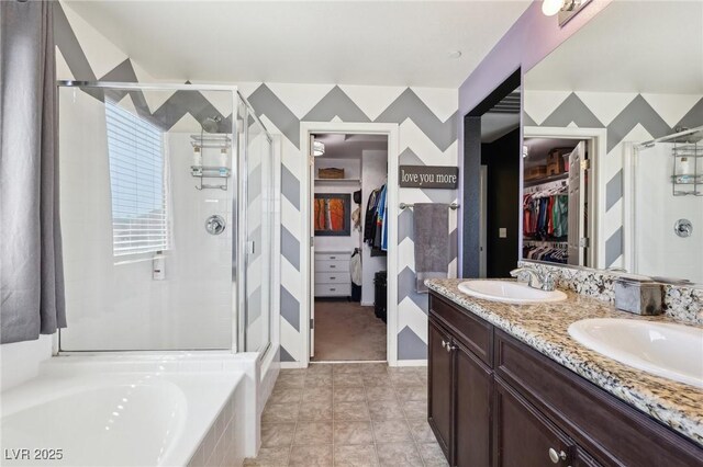 full bathroom with a walk in closet, a garden tub, double vanity, a sink, and a shower stall