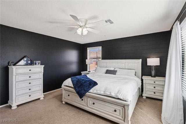 bedroom with light carpet, an accent wall, visible vents, and baseboards