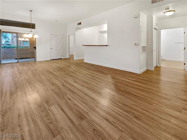 unfurnished living room featuring an inviting chandelier, visible vents, light wood-style floors, and baseboards