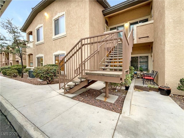 entrance to property with stucco siding, central AC, and a patio area