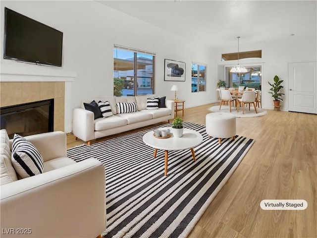 living area with a fireplace, an inviting chandelier, wood finished floors, and baseboards