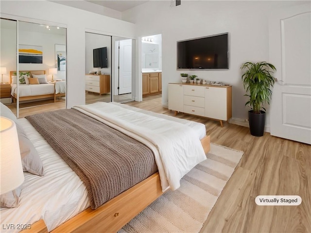 bedroom with two closets, visible vents, light wood finished floors, and connected bathroom