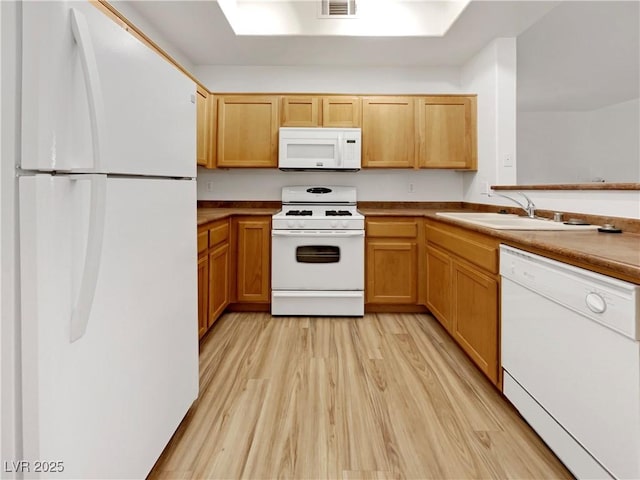 kitchen with white appliances, visible vents, light wood-type flooring, and a sink