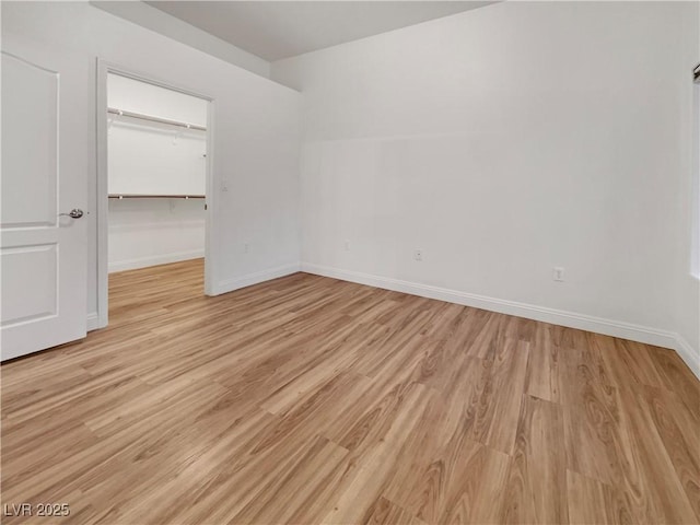 unfurnished bedroom with light wood-type flooring, baseboards, a closet, and a spacious closet