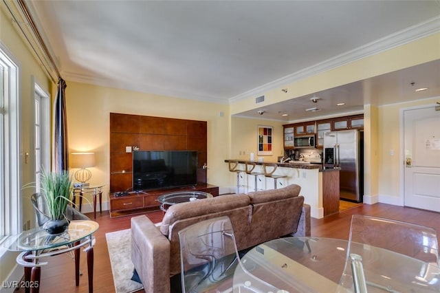 living area with baseboards, dark wood-style flooring, visible vents, and crown molding