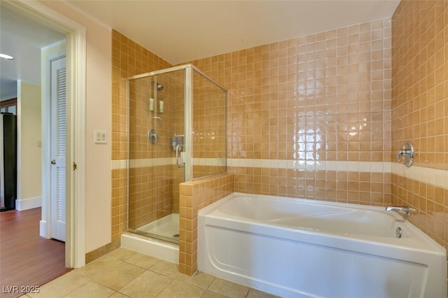 full bathroom featuring tile walls, a garden tub, a shower stall, and tile patterned floors