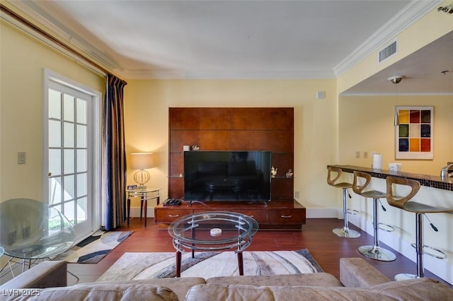 living room featuring ornamental molding, visible vents, plenty of natural light, and wood finished floors