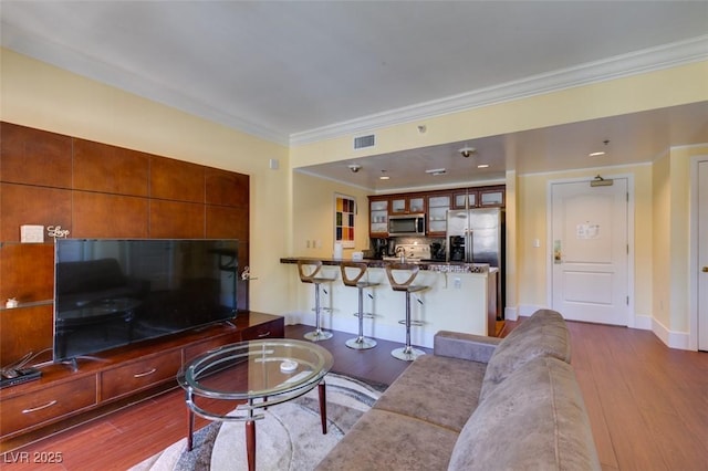 living room featuring baseboards, visible vents, dark wood finished floors, and crown molding