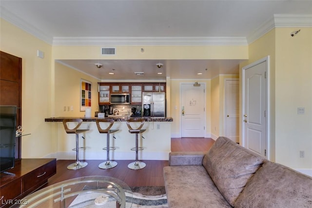 living room with dark wood-style flooring, visible vents, and crown molding