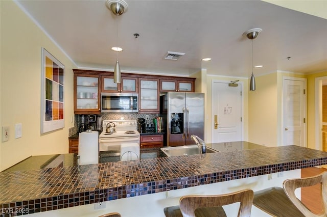 kitchen featuring a sink, visible vents, appliances with stainless steel finishes, decorative backsplash, and dark countertops