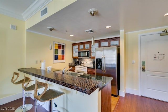 kitchen featuring visible vents, dark countertops, a breakfast bar, a peninsula, and stainless steel appliances