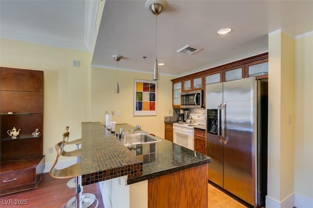 kitchen with ornamental molding, a breakfast bar, a peninsula, stainless steel appliances, and a sink