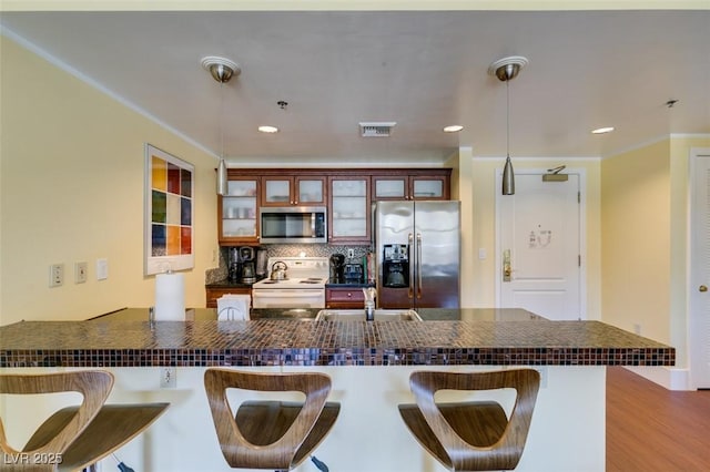 kitchen featuring stainless steel appliances, dark countertops, tasteful backsplash, visible vents, and hanging light fixtures