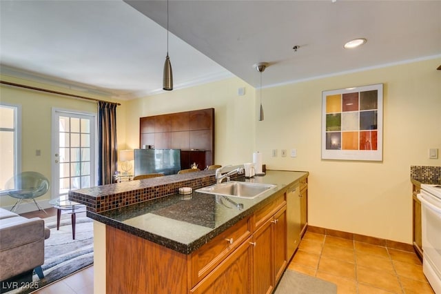 kitchen featuring a peninsula, a sink, hanging light fixtures, stainless steel dishwasher, and brown cabinets