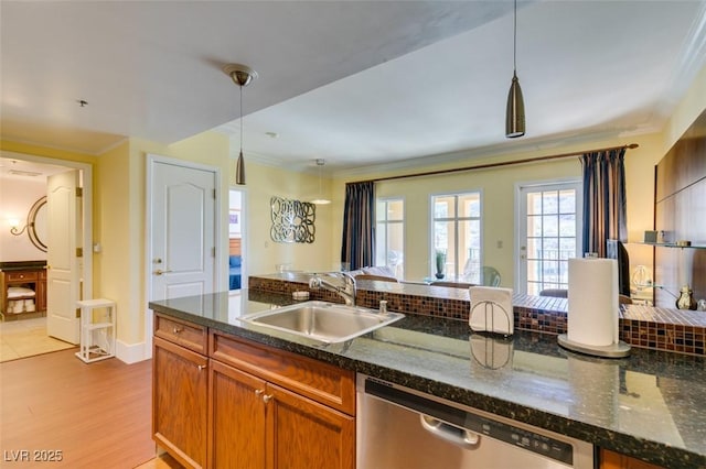 kitchen featuring dishwasher, light wood-style flooring, ornamental molding, hanging light fixtures, and a sink