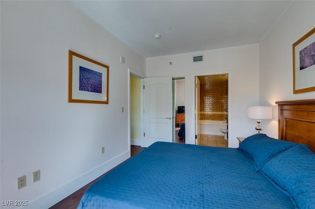 bedroom featuring wood finished floors, connected bathroom, visible vents, and baseboards