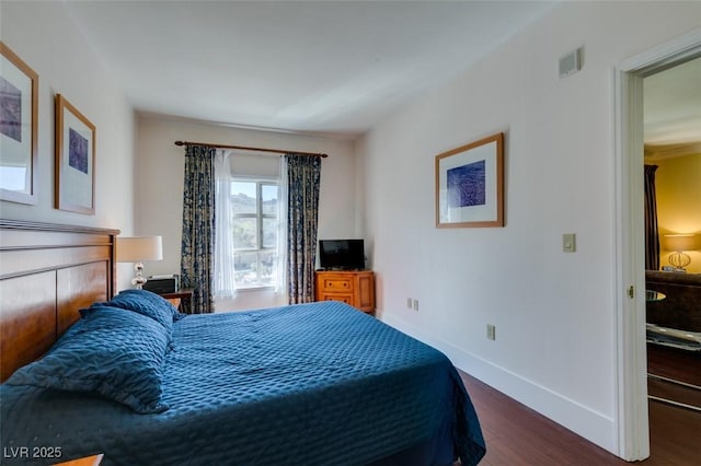 bedroom with dark wood-type flooring and baseboards