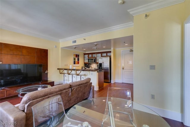 living area with baseboards, visible vents, dark wood finished floors, and crown molding