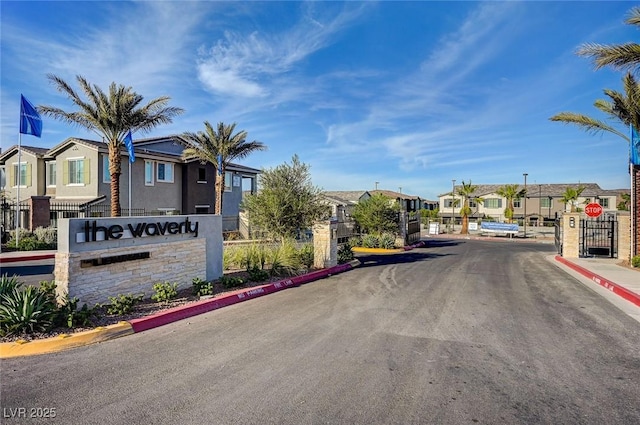 view of street with traffic signs, a gate, a gated entry, a residential view, and curbs