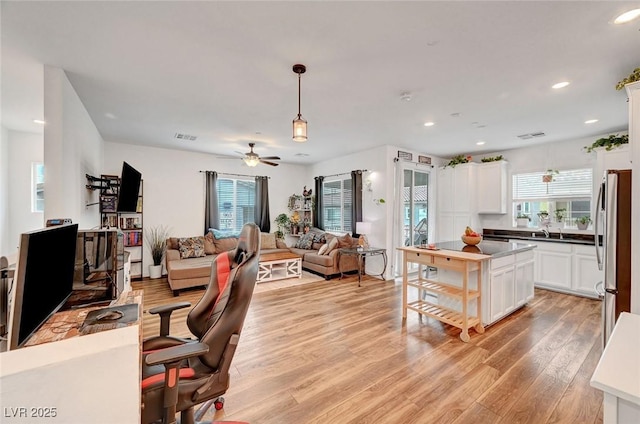 home office with light wood-type flooring, plenty of natural light, a sink, and recessed lighting