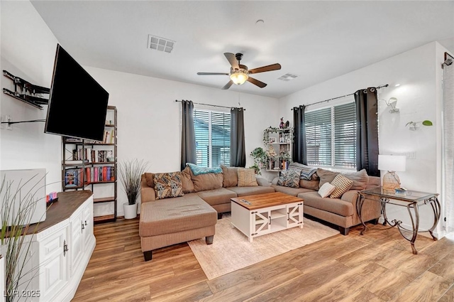 living area featuring light wood finished floors, visible vents, and a ceiling fan