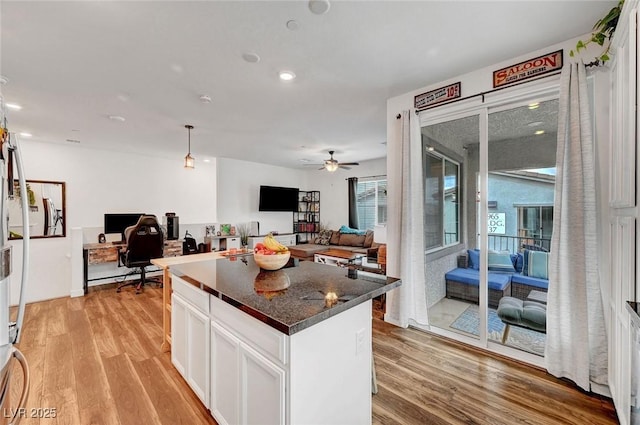 kitchen featuring open floor plan, light wood finished floors, a kitchen island, and white cabinetry