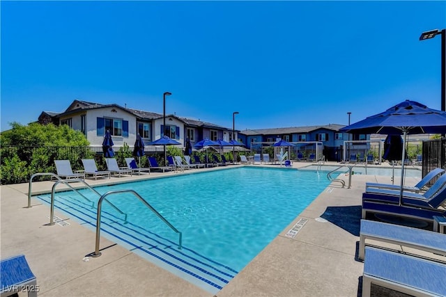 pool with a patio, fence, and a residential view