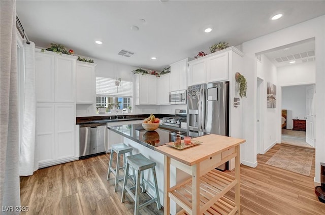 kitchen with stainless steel appliances, white cabinets, visible vents, and light wood-style flooring