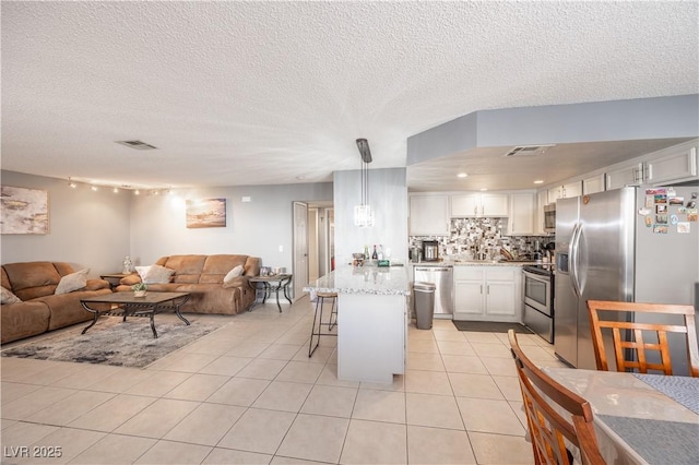 kitchen with open floor plan, appliances with stainless steel finishes, light tile patterned floors, and visible vents