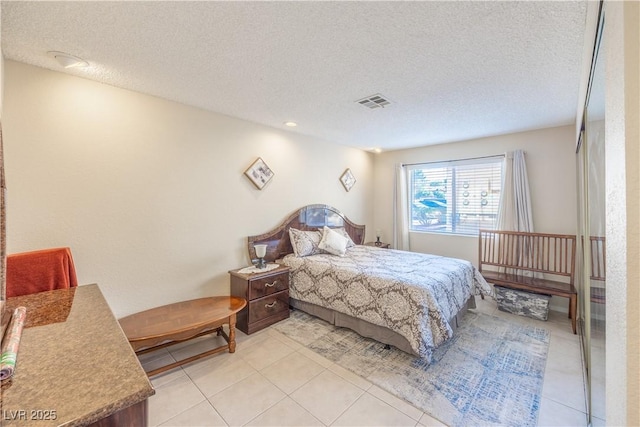 bedroom with a textured ceiling, light tile patterned floors, and visible vents