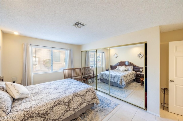 bedroom with visible vents, a textured ceiling, and light tile patterned flooring