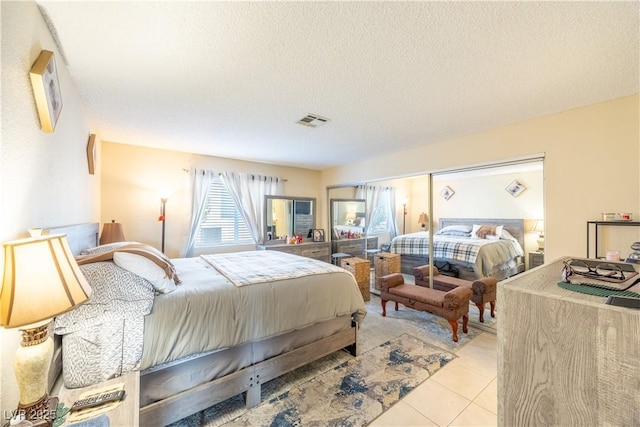 bedroom with a textured ceiling, visible vents, and tile patterned floors