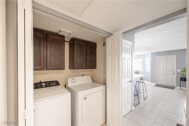 clothes washing area with cabinet space, separate washer and dryer, a textured ceiling, and light tile patterned flooring