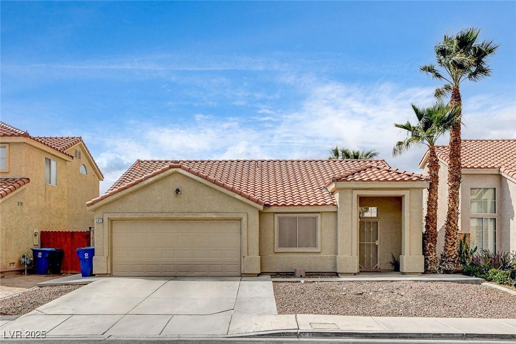 mediterranean / spanish-style house with driveway, an attached garage, a tile roof, and stucco siding