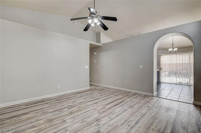 unfurnished room with arched walkways, vaulted ceiling, ceiling fan with notable chandelier, and wood finished floors