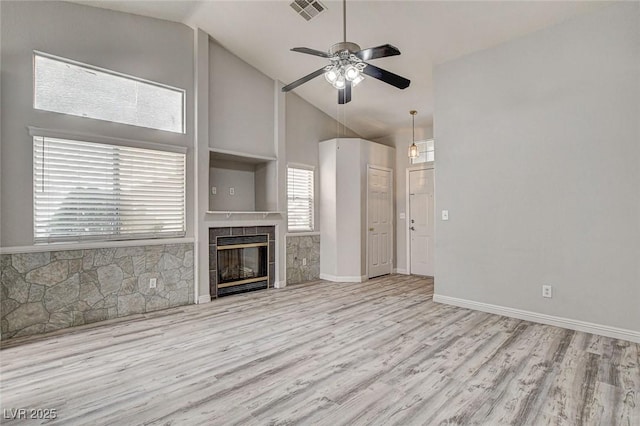 unfurnished living room with a fireplace, visible vents, ceiling fan, wood finished floors, and high vaulted ceiling