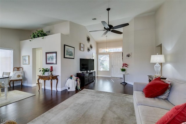 living area featuring high vaulted ceiling, dark wood-type flooring, visible vents, and baseboards