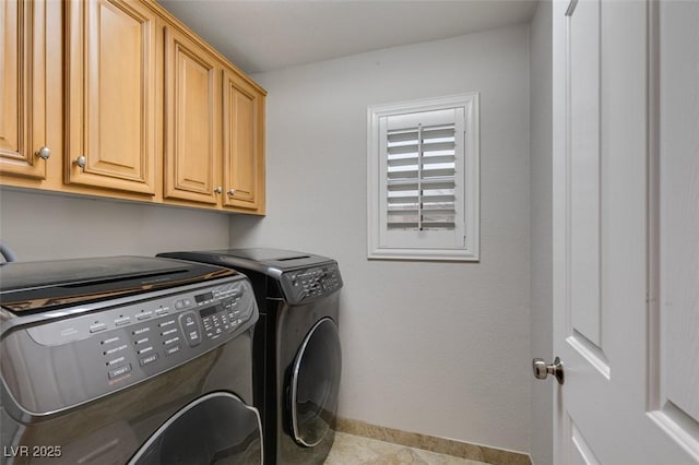 clothes washing area with washer and clothes dryer, cabinet space, and baseboards