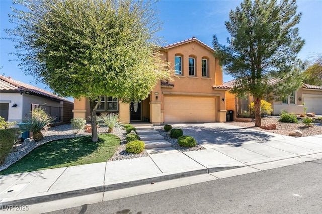 mediterranean / spanish home featuring a garage, driveway, a tiled roof, and stucco siding