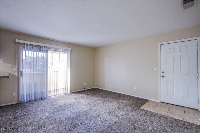 interior space featuring light tile patterned floors, baseboards, visible vents, and light colored carpet