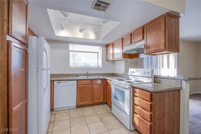 kitchen featuring under cabinet range hood, white appliances, a sink, visible vents, and a tray ceiling