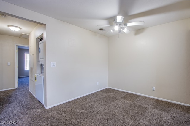 unfurnished room featuring visible vents, baseboards, dark colored carpet, and stacked washer / drying machine